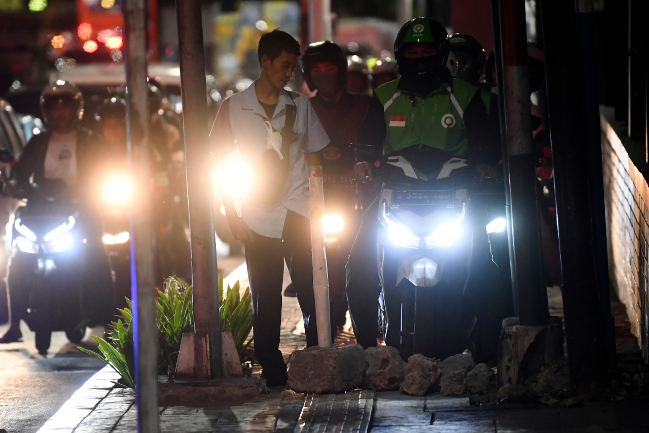 Seorang karyawan swasta, Arif menghalau sepeda motor yang menaiki trotoar dengan memasang batu di Jalan Menteng Raya, Jakarta, Senin (18/11/2019). Aksi tersebut dilakukan karena masih banyak pengendara sepeda motor menaiki trotoar yang dikhususkan untuk pejalan kaki untuk menghindari macet. Foto Pilihan Pekan Ketiga November 2019