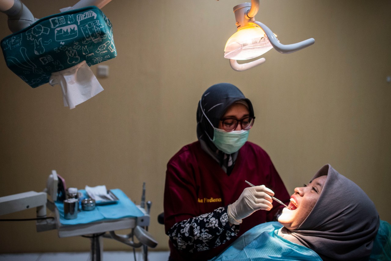 drg Dita Firdiana (kiri) melakukan perawatan gigi pasien di Klinik Gigi Difa Oral Health Center, Kompleks Golden Plaza Blok C Nomor 5, Gandaria, Jakarta, Rabu (20/11/2019). Klinik gigi yang didirikan oleh tiga dokter gigi yaitu Dita Firdiana, Widya Apsari dan Arfina Arief itu sejak bulan Juni 2015 juga melayani orang dengan HIV AIDS (ODHA) yang bertujuan untuk memberikan layanan akses kesehatan yang lebih manusiawi bagi setiap orang. Foto Pilihan Pekan Ketiga November 2019