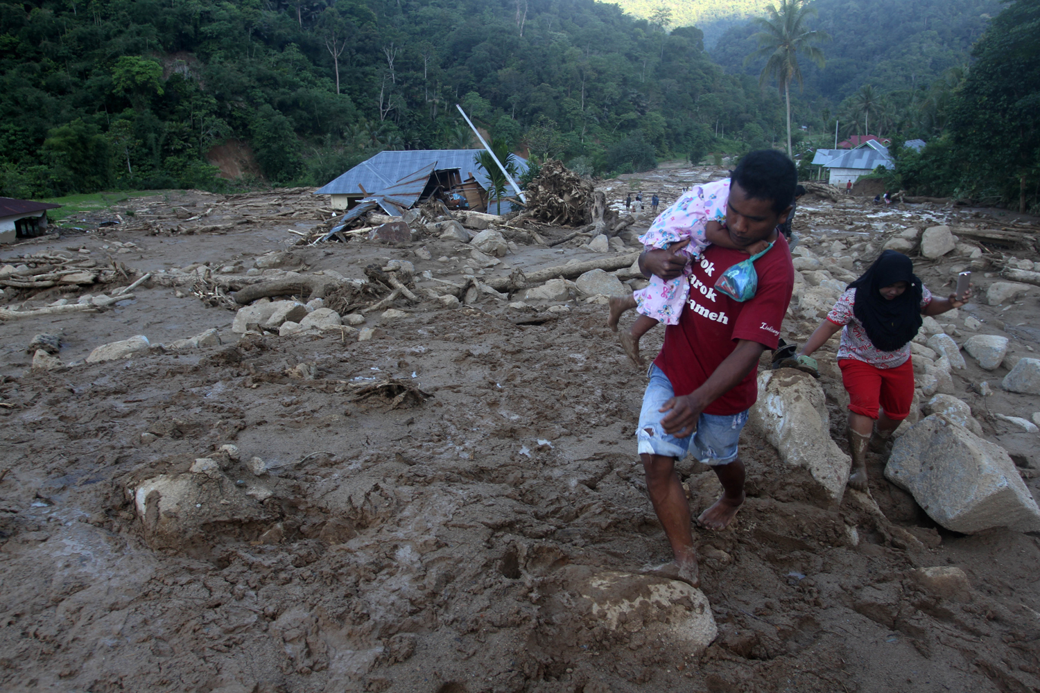 Warga berjalan diantara material sisa banjir bandang di desa Sapan Salak dan Desa Manggih, Kecamatan Koto Parik Gadang di Ateh, Kabupaten Solok Selatan, Sumatera Barat, Senin (25/11/2019). Intensitas curah hujan lebat yang terjadi pada minggu malam (24/11/2019) memicu terjadinya banjir bandang yang merusak 25 unit rumah warga di dua desa, sembilan diantaranya rusak berat, serta fasilitas umum juga mengalami kerusakan, tidak ada korban jiwa dalam peristiwa ini. Foto Pilihan Pekan Keempat November 2019