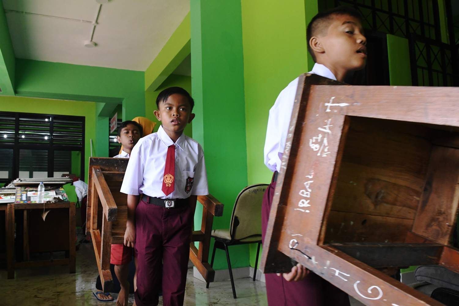 Siswa Sekolah Dasar Negeri Kapuk Muara 01 bergotong royong memindahkan meja, kursi, dan lemari kedalam ruang kelas saat kerja bakti bersama pasca banjir di Jakarta, Senin (6/1/2019). Kegiatan belajar mengajar di sejumlah sekolah terdampak banjir belum efektif karena selain ruangan kelas terendam air juga digunakan sebagai tempat pengungsian. Foto Pilihan Pekan Kedua Januari 2020