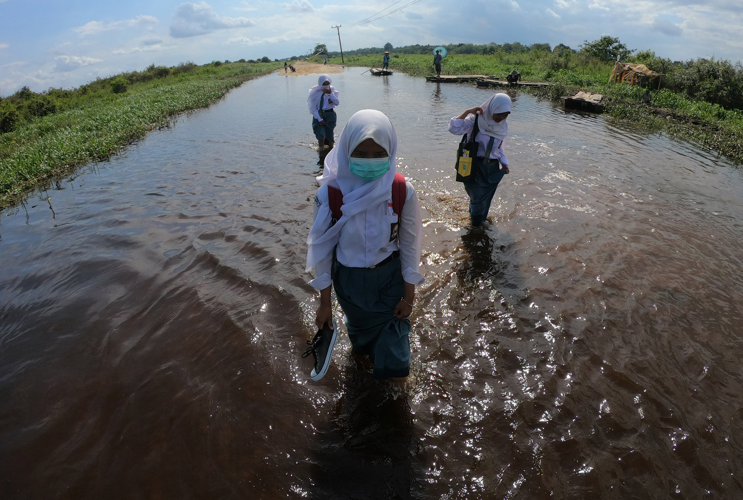 Sejumlah pelajar melewati jalan penghubung Desa Jebus dengan Desa Gedong Karya yang terendam banjir luapan Sungai Batanghari di Muarojambi, Jambi, Selasa (7/1/2020). Ruas jalan penghubung desa satu-satunya tersebut terendam banjir sejak dua pekan terakhir. Foto Pilihan Pekan Kedua Januari 2020