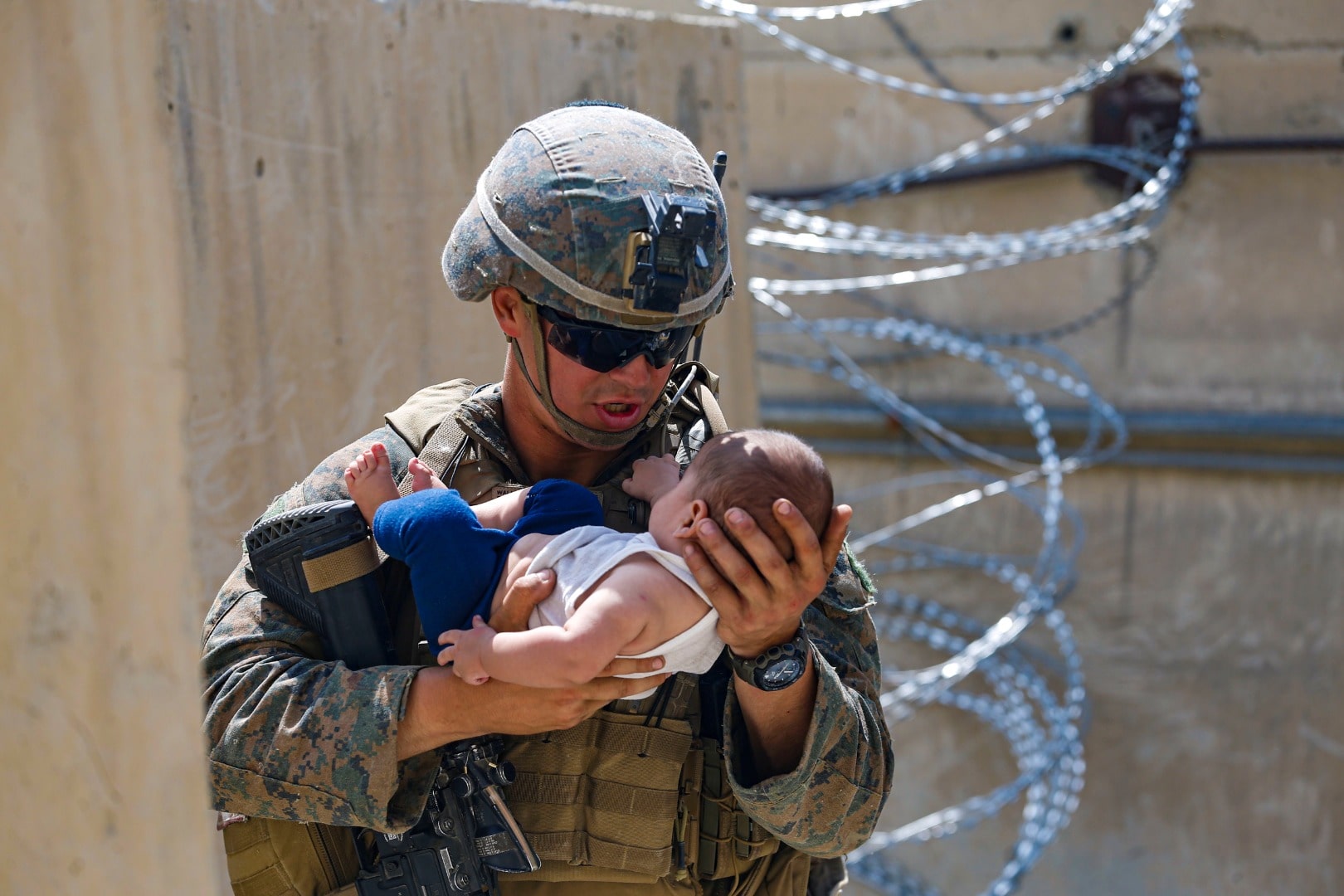 Seorang marinir AS menenangkan bayi saat mereka menunggu si ibu saat evakuasi di Bandara Internasional Hamid Karzai, Afganistan, Sabtu