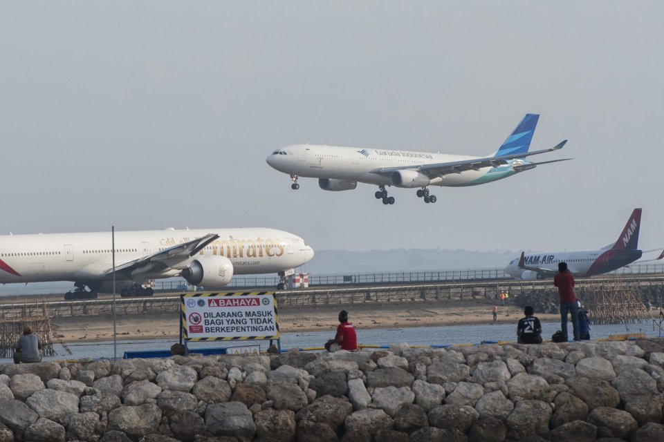 Sejumah wisatawan menyaksikan pergerakan pesawat di landasan pacu Bandara Ngurah Rai dari Pantai Patra Bali, Kuta, Selasa (15/5).