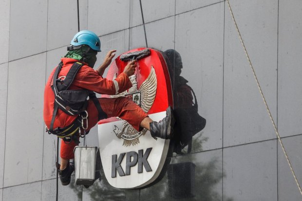Seorang pekerja sedang membersihkan logo KPK di Jakarta, Rabu (21/11).