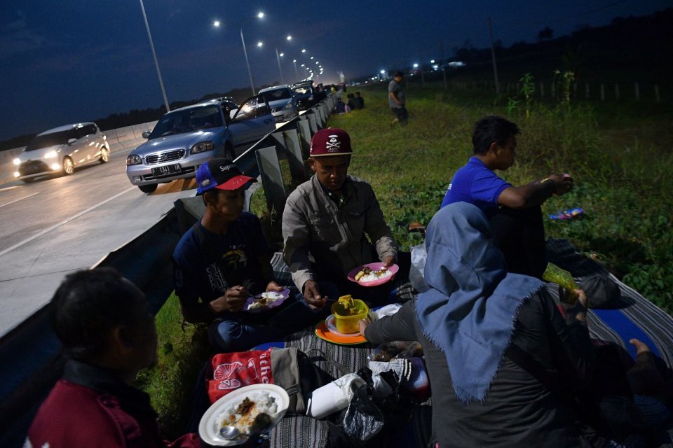 Pemudik menyantap makanan untuk berbuka puasa di pinggir ruas jalan tol Pejagan-Pemalang, Tegal, Jawa Tengah, Kamis (30/5/2019). 