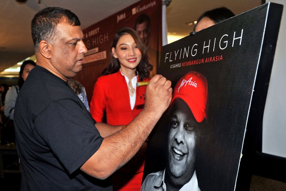 CEO AirAsia Group Tony Fernandes (kiri), menandatangani poster saat peluncuran bukunya yang berjudul Flying High: Kisahku Membangun AirAsia, di Jakarta, Kamis (4/7/2019). Buku tersebut mengisahkan perjalanan hidup Tony Fernandes dari mulai bekerja sebagai