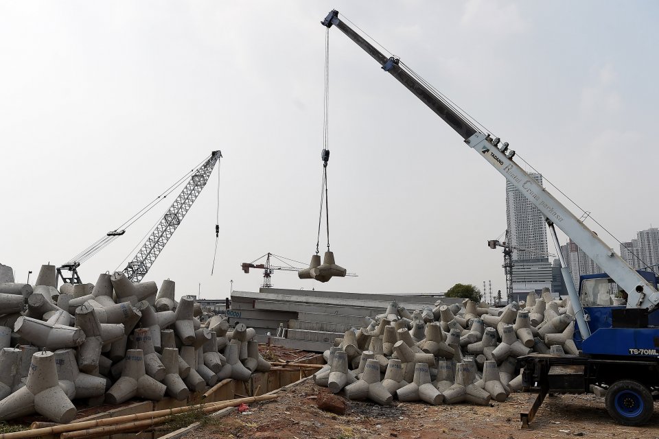 Pekerja mengoperasikan alat berat untuk memindahkan beton \"tetrapod\" atau pemecah ombak ke kapal tongkang di Pelabuhan Dermaga Kali Adem, Muara Angke, Jakarta, Selasa (9/7/2019). Dinas Ketahanan Pangan, Kelautan, dan Pertanian (KPKP) DKI Jakarta mem