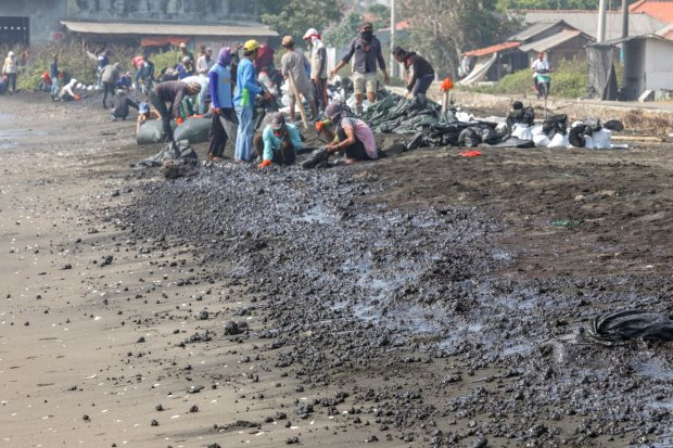 Warga mengumpulkan limbah tumpahan minyak \"Oil Spill\" yang tercecer milik Pertamina di Pesisir Pantai Cemarajaya, Karawang, Jawa Barat, Rabu (24/7/2019). Pasir yang tercemar minyak tersebut dikumpulkan dan akan dipindahkan ke pabrik penyimpanan limb