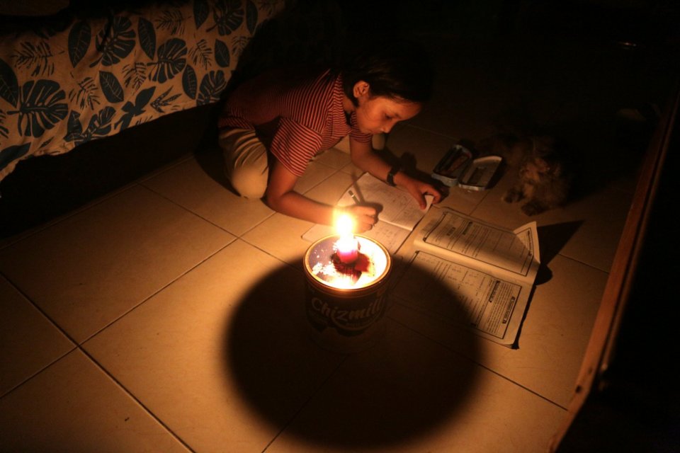 Seorang anak perempuan belajar saat listrik mati di kawasan Bekasi, Jawa Barat (4/8). Listrik padam lebih dari 10 jam.