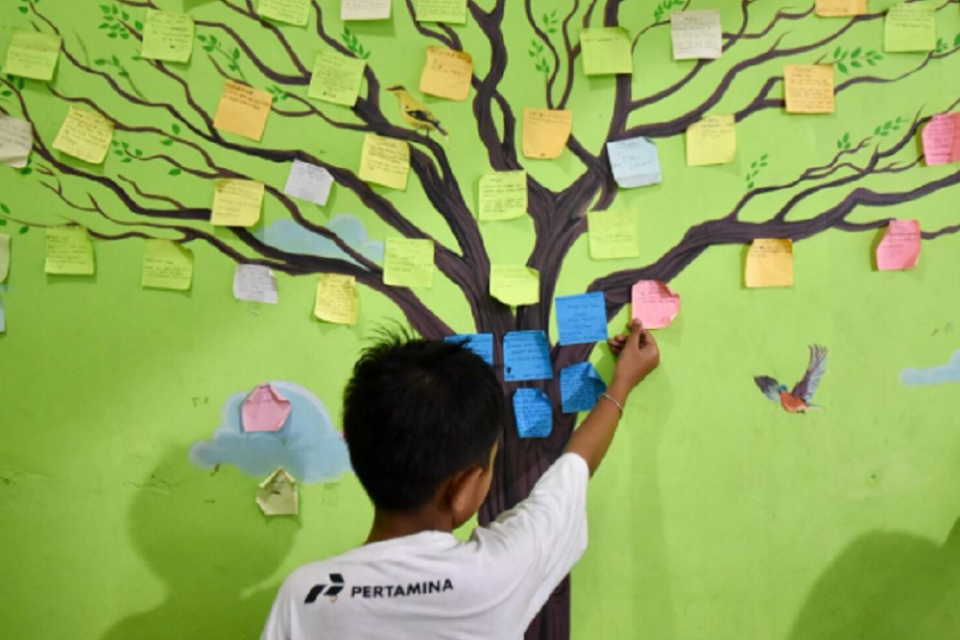  Seorang anak sedang menempel kertas di pohon. Pertamina menggelar tiga program Corporate Social Responsibility (CSR) dengan menggandeng sejumlah kelompok serta instansi setempat guna memberdayakan serta membantu pemulihan trauma para ibu dan anak-anak di