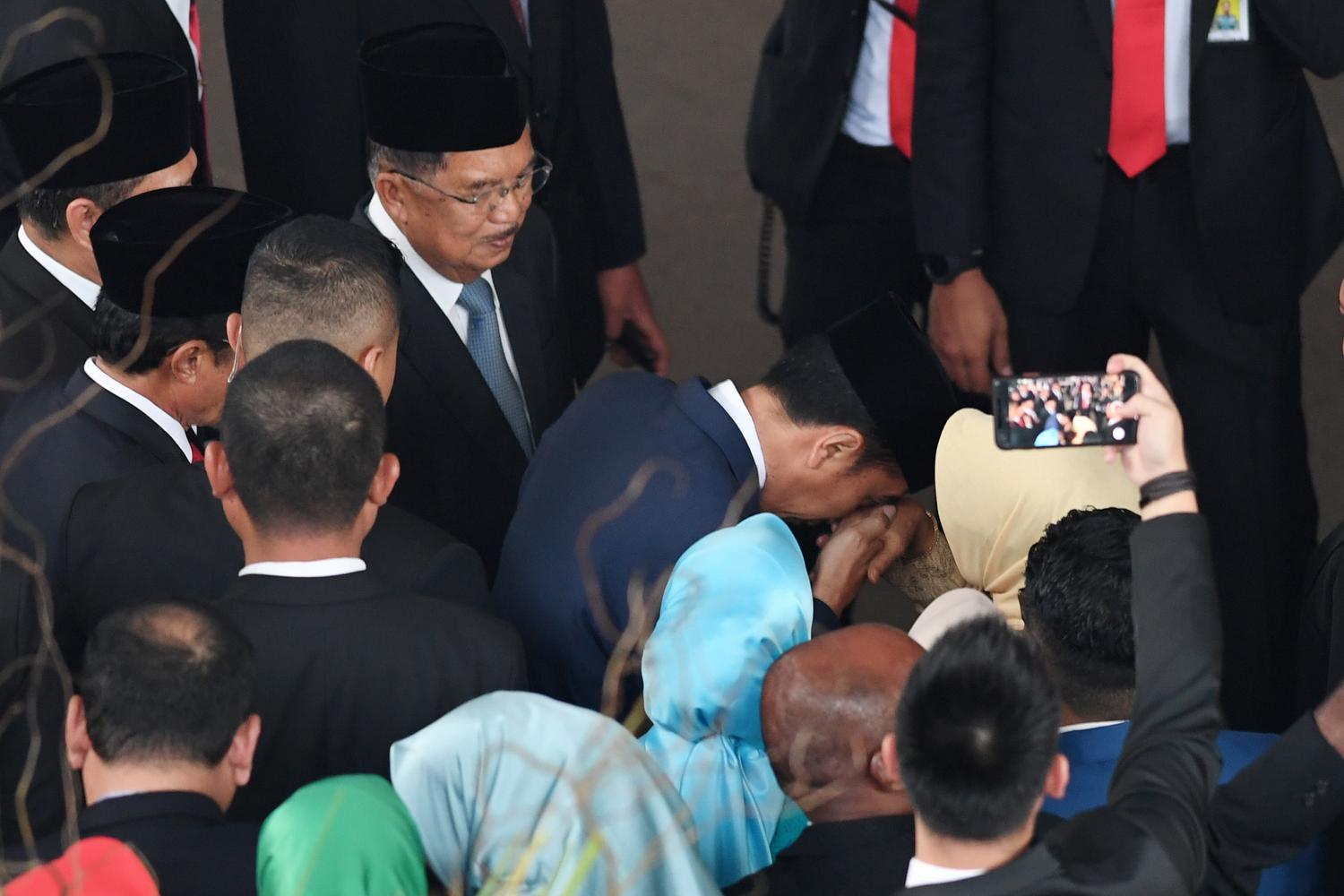 Presiden Joko Widodo (kedua kanan) mencium tangan ibunda Sudjiatmi (kanan) disaksikan mantan Wakil Presiden Jusuf Kalla usai pelantikan presiden dan wapres periode 2019-2024 kompleks Parlemen Senayan, Jakarta, Minggu (20/10/2019). Pada Rabu (25/3), Ibunda