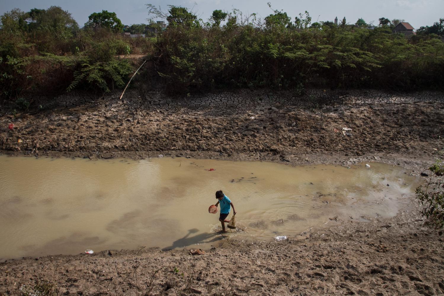 Seorang anak bermain di dasar sungai yang kering di Desa Wirun, Mojolaban, Sukoharjo, Jawa Tengah, Kamis (26/9/2019). Sungai yang menjadi sumber air irigasi lahan pertanian warga tersebut kering karena musim kemarau sehingga petani terpaksa membuat sumur 