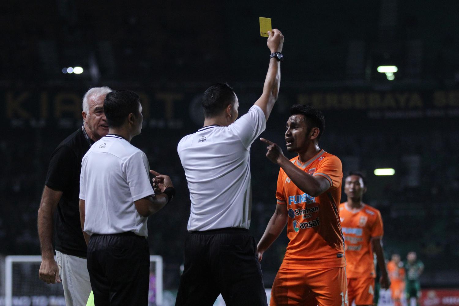 Pesepak bola Borneo FC Abrizal Umanailo (kanan) mendapat kartu kuning dari wasit Fariq Hitaba (tengah)saat pertandingan Liga 1 2019 melawan Persebaya di Stadion Gelora Bung Tomo, Surabaya, Jawa Timur, Jumat (11/10/2019). Persebaya bermain imbang dengan Bo
