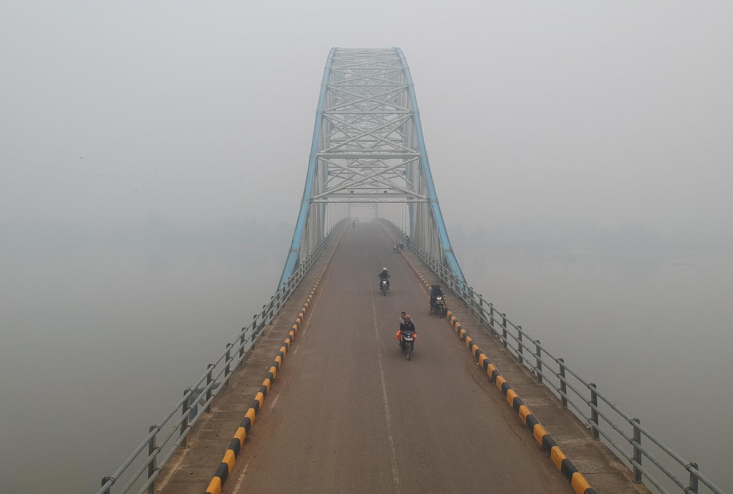 Pengendara melintasi Jembatan Muara Sabak yang diselimuti kabut asap karhutla di Muara Sabak Barat, Tanjungjabung Timur, Jambi.