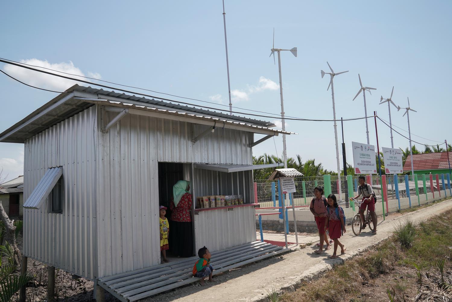 Warga beraktivitas di sekitar lokasi pembangkit listrik tenaga surya dan angin yang menjadi sumber listrik utama di Dusun Bondan, Kampung Laut, Cilacap, Jawa Tengah, Kamis (24/10/2019). Sebanyak 37 Kepala Keluarga memanfaatkan suplai listrik dari pembangk