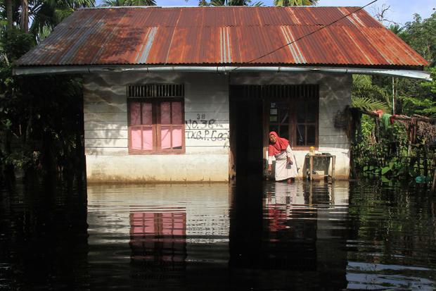 Warga berada di depan rumahnya yang terendam banjir di Desa Gunong Pulo, Kecamatan Arongan Lam Balek, Aceh Barat, Aceh, Kamis (31/10/2019). Banjir yang disebabkan tingginya intensitas hujan sejak dua pekan terakhir menyebabkan ratusan rumah warga dan ratu