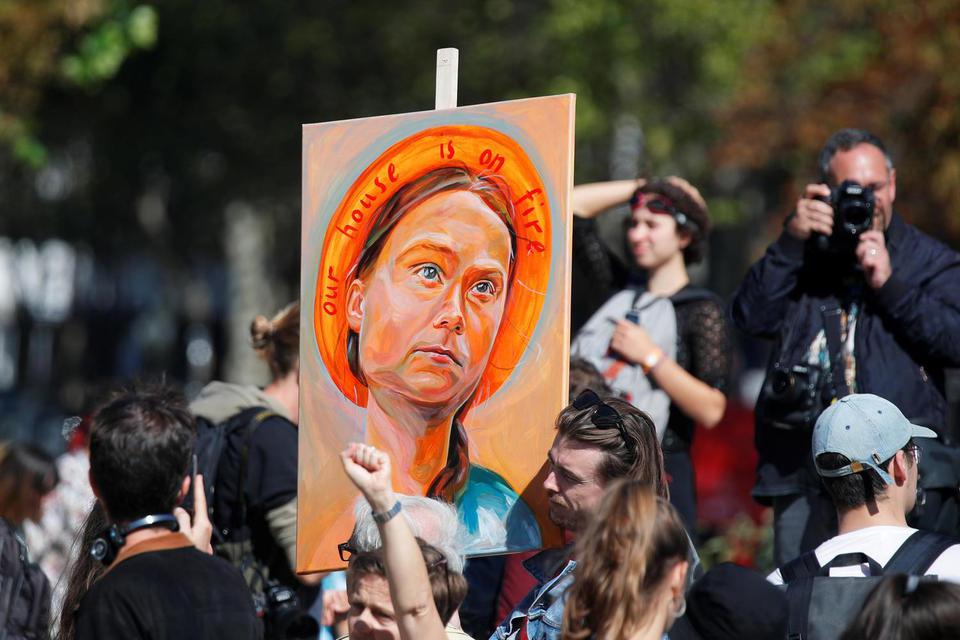 Seorang pria membawa poster bergambar aktivis iklim Swedia Greta Thunberg saat warga berpartisipasi dalam aksi protes perubahan iklim "Fridays for Future" di Paris, Prancis, Jumat (20/9/2019).