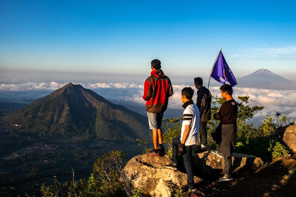 Sejumlah wisatawan menikmati pemandangan Gunung Merbabu (kiri) dan Gunung Andong (kanan) dari Gunung Telomoyo, Desa Sepakung, Banyubiru, Kabupaten Semarang, Jawa Tengah, Minggu (10/11/2019).