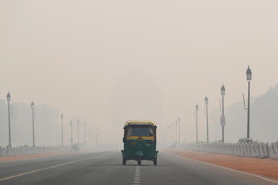 Becak otomatis berkendara melewati Gerbang India pada pagi hari berkabut asal di New Delhi, India, Senin (11/11/2019).