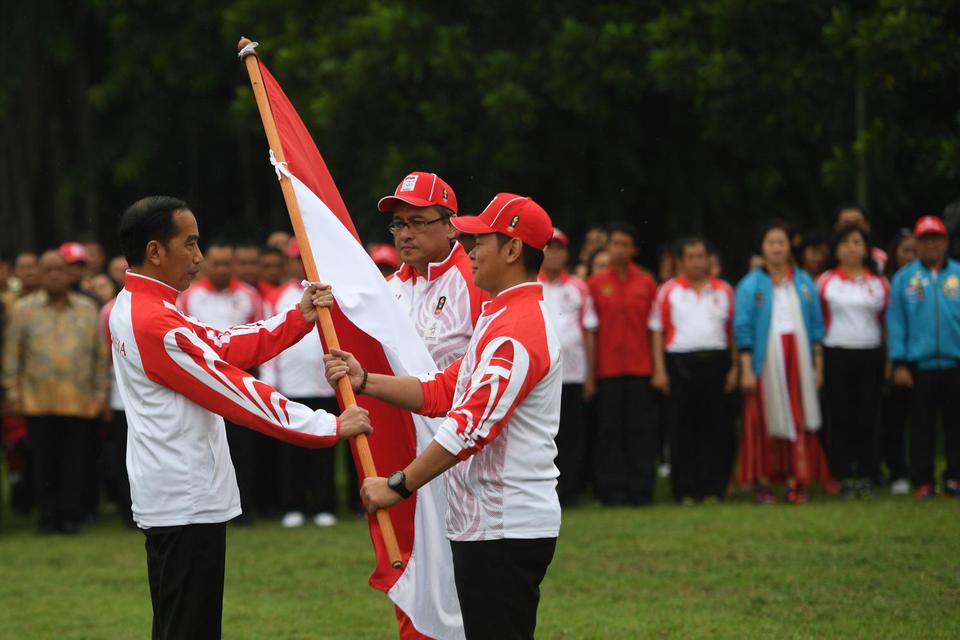 Presiden Joko Widodo (kiri) menyerahkan bendera kepada Ketua Komite Olimpiade Indonesia (KOI) Raja Sapta Oktohari (kanan) disaksikan Ketua Kontingen Indonesia Harry Warganegara (tengah) saat pelepasan atlet untuk SEA Games 2019 di Istana Bogor, Jawa Barat