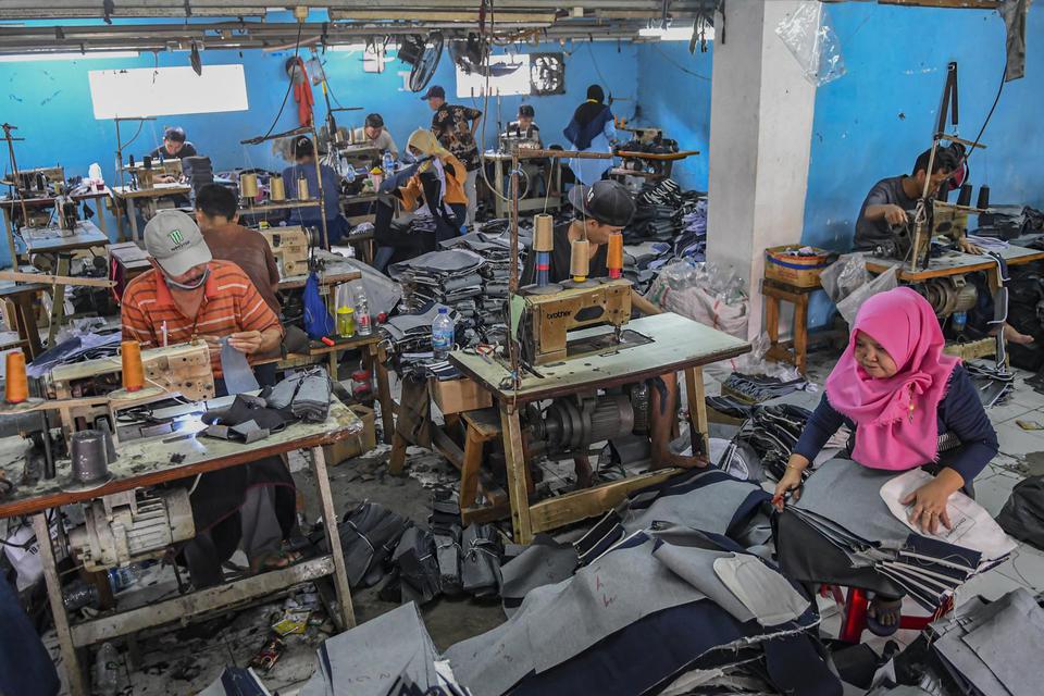 Pekerja menyelesaikan pembuatan celana panjang di kawasan PIK, Jakarta, Jumat (27/12/2019). 