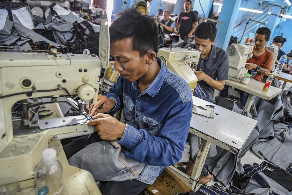 Pekerja menyelesaikan pembuatan celana panjang di kawasan PIK, Jakarta, Jumat (27/12/2019). 