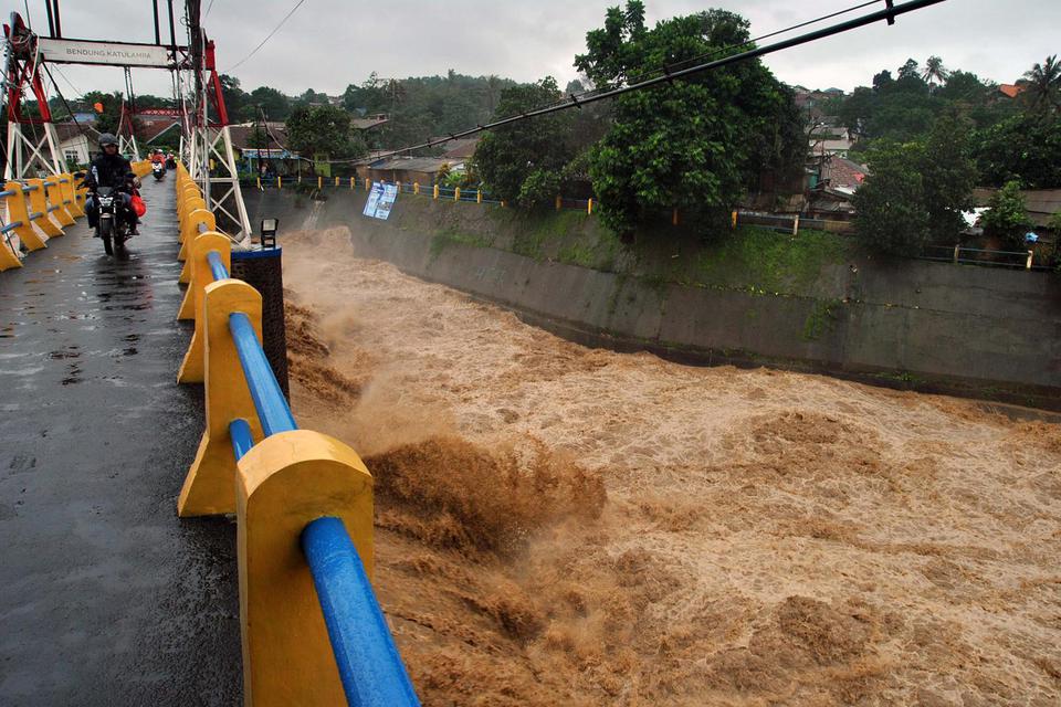 Pengendara motor melintas diatas jembatan saat tinggi muka air sungai Ciliwung naik di Bendung Katulampa, Kota Bogor, Jawa Barat, Rabu (1/1/2020). Hujan dengan intensitas tinggi yang mengguyur wilayah Bogor dan sekitarnya sejak Selasa (31/12/2019) malam t