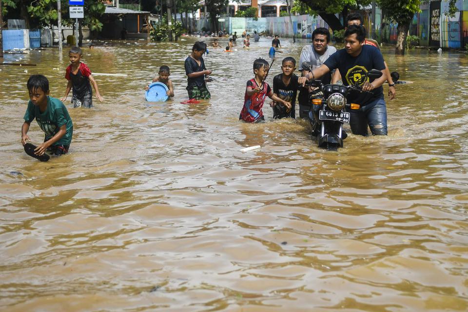 Warga melintasi banjir di kawasan Bukit Duri, Jakarta, Kamis (2/1/2020). Banjir tersebut akibat luapan sungai Ciliwung.