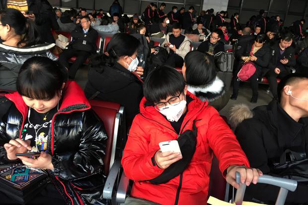 Para penumpang memakai masker terlihat di ruang tunggu untuk kereta menuju Wuhan di Stasiun Kereta Api Beijing Barat, menjelang Tahun Baru Imlek di Beijing, China, Senin (20/1/2020).
