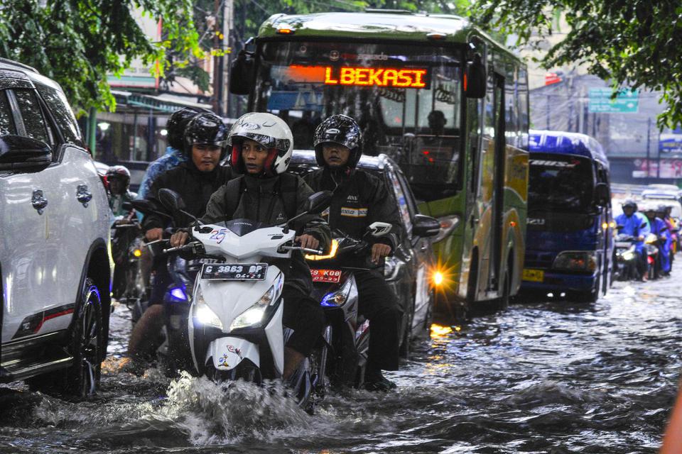Sejumlah pengendara kendaraan bermotor melintasi jalan Ir Juanda yang tergenang air di Bekasi, Jawa Barat, Senin (10/2/2020). Curah hujan yang tinggi dan kualitas drainase yang buruk membuat jalan Ir.Juanda tergenang air setinggi 20-30 cm.
