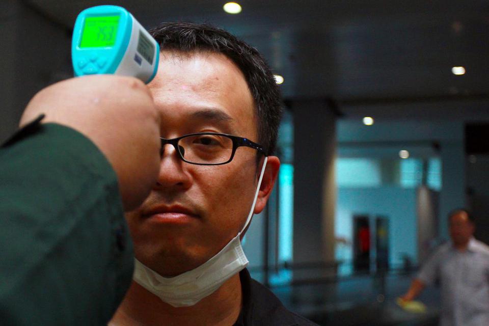 Petugas dari Kantor Kesehatan Pelabuhan (KKP) Klas 1 Soetta melakukan pemeriksaan suhu tubuh seorang penumpang yang berasal dari Singapura setibanya di Terminal 3 Bandara Soekarno Hatta, Tangerang, Banten, Senin (10/2/2020). 