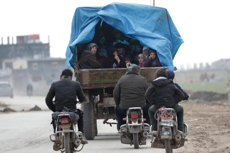 Warga yang mengungsi, meninggalkan Idlib, berada di atas truk dengan harta benda mereka di Azaz, Suriah, Sabtu (15/2/2020).