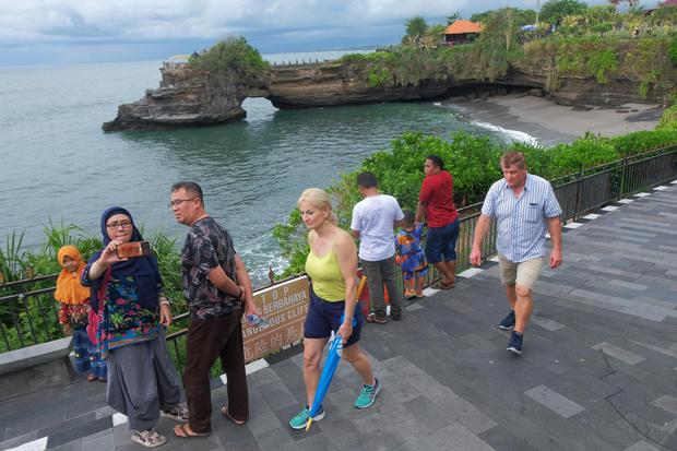 Wisatawan menikmati pemandangan di area objek wisata Tanah Lot, Tabanan, Bali, Minggu (16/2/2020). Dinas Pariwisata Bali menaksir kehilangan pendapatan dari pariwisata sekitar Rp10 miliar dalam waktu hampir sebulan akibat pembatalan kunjungan sekitar 20.0