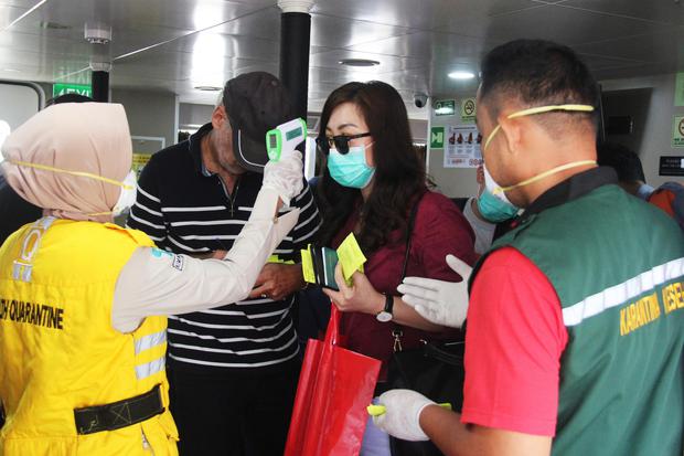 Petugas otoritas kesehatan memeriksa suhu tubuh seorang penumpang kapal dari Malaysia menggunakan termometer non kontak di Pelabuhan Internasional PT Pelindo I Dumai di Dumai, Riau, Minggu (23/2/2020). Pemerintah Indonesia memberikan perhatian serius ter