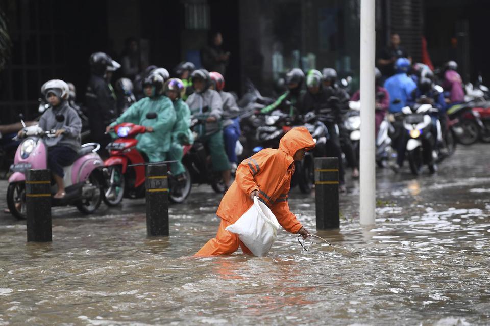 Petugas PPSU membersihkan sampah saat banjir di kawasan Kemang Raya, Jakarta, Selasa (25/2/2020).
