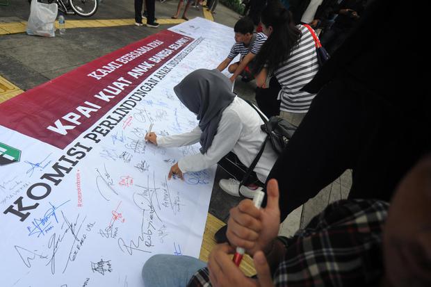 Warga membubuhkan tanda tangan saat aksi simpatik mendukung penguatan Komisi Perlindungan Anak Indonesia (KPAI) oleh mahasiswa dari berbagai organisasi ekstra kampus pada Hari Bebas Kendaraan Bermotor di Jalan MH Thamrin, Jakarta, Minggu (1/3/2020).