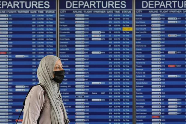 Kevin Lamarque Seorang perempuan berjalan melewati layar jadwal keberangkatan di Bandara Internasional Dulles, sehari setelah Presiden Amerika Serikat Donald Trump mengumumkan pembatasan penerbangan dari Eropa ke Amerika Serikat selama 30 hari untuk menc