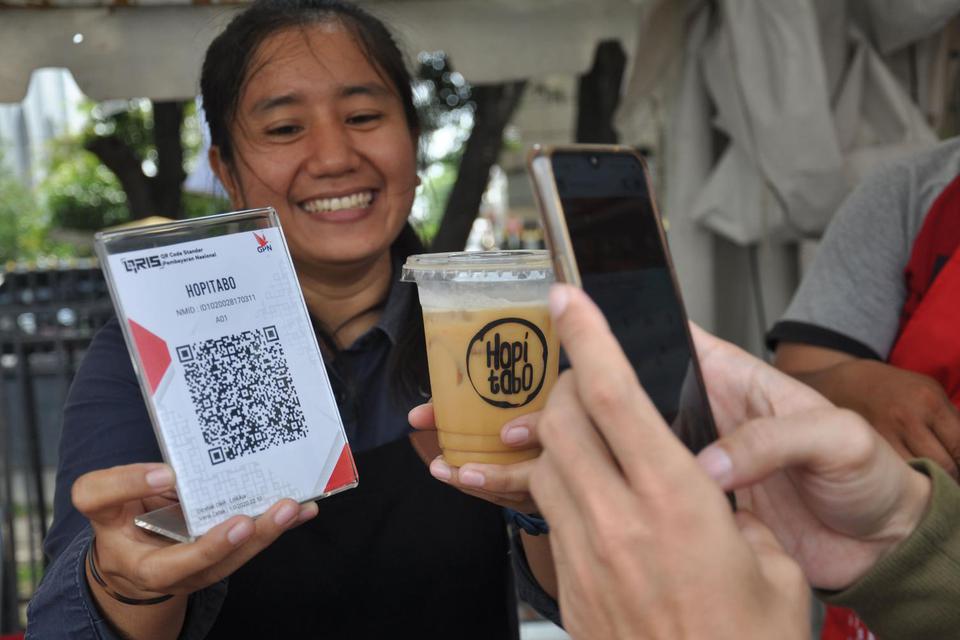 Ilustrasi, pedagang minuman kopi melayani pembayaran non tunai menggunakan Quick Response Indonesia Standard (QRIS). BI mencatat merchant yang mengadopsi QRIS hingga pertengahan April 2020 mencapai 3,7 juta.