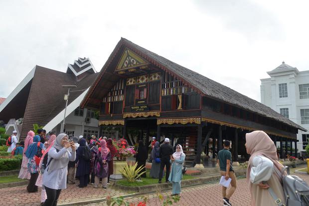 Rombongan wisatawan mengunjungi rumah adat Aceh.
