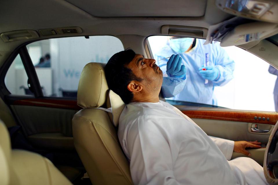 Ahmed Jadallah Petuas media dengan sarung tangan peindung menyeka seorang pria pada drive-thru tes COVID-19 di pusat penyaringan di Abu Dhabi, Uni Emirat Arab, Senin (30/3/2020).