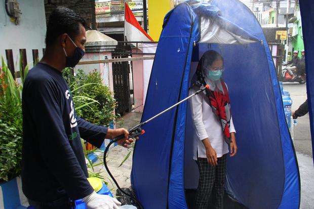 Warga menyemprotkan disinfektan pada seorang pemakai jalan sebelum masuk di Kelurahan Ketawanggede, Malang, Jawa Timur, Rabu (1/4/2020). Warga di kawasan tersebut secara swadaya melakukan screening kepada para pengguna jalan dengan menyemprotkan disinfek