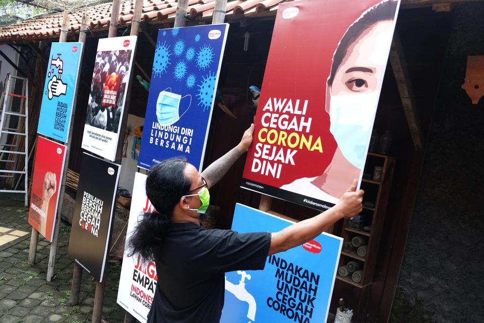 Relawan memasang poster bertajuk Desain Poster untuk Indonesia Bersama Lawan Corona di halaman Roemah Rakyat, Banjarsari, Solo, Jawa Tengah, Rabu (1/4/2020). Desain poster yang juga dipamerkan di sosial media tersebut dibuat sebagai media informasi, eduka