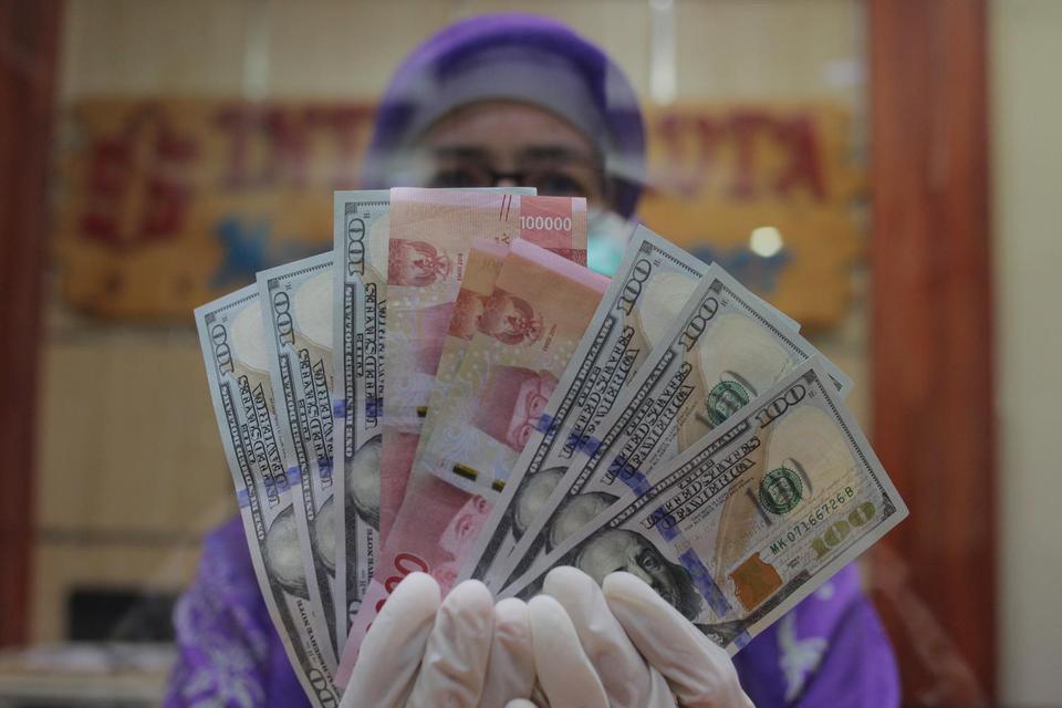 Petugas menunjukkan uang rupiah dan dolar AS di salah satu gerai penukaran mata uang asing di Jakarta, Kamis (2/4/2020). Nilai tukar rupiah terhadap dolar Amerika Serikat (AS) bergerak melemah pada penutupan perdagangan Kamis (2/4) sebesar 45 poin atau 0,