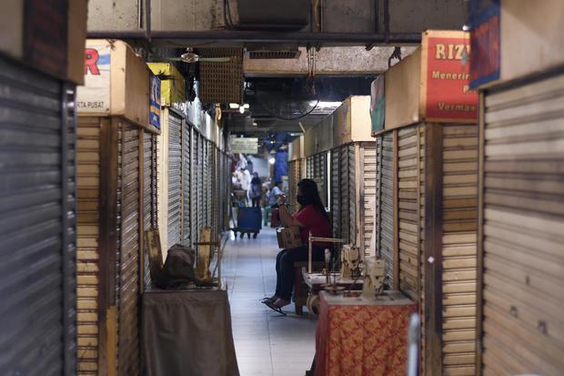 Seorang warga duduk di antara pertokoan yang tutup di Pasar Baru, Jakarta, Jumat (3/4/2020). Sebagian besar pertokoan menutup usahanya sesuai edaran pemerintah untuk mengantisipasi penyebaran virus corona atau COVID-19.