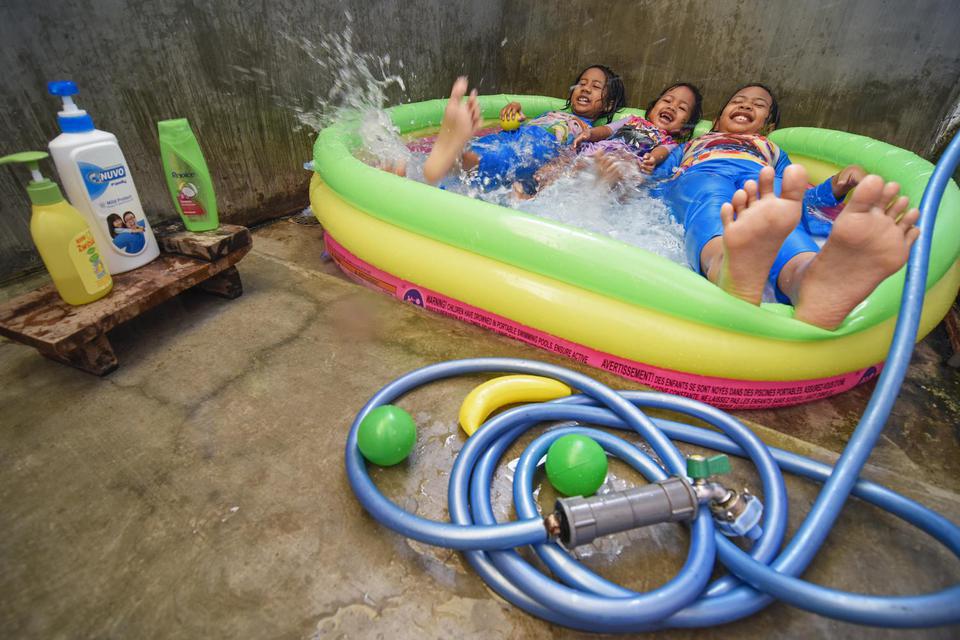 Sejumlah anak bermain menggunakan kolam renang mainan di rumahnya di Kelurahan Ampenan Tengah, Mataram, NTB, Minggu (5/4/2020). Pemerintah mengimbau masyarakat untuk bekerja dan belajar dari rumah saja serta tak menyalahgunakan hal tersebut untuk pergi be