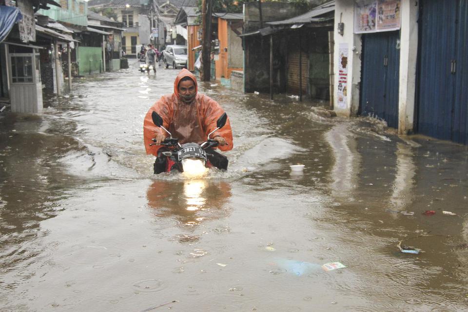 Pengendara motor melintasi banjir di Kampung Panjang, Citayem, Depok, Jawa Barat, Minggu (5/4/2020). 