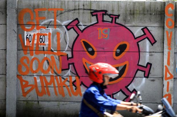 Pengendara melintas di depan mural tentang pandemi virus corona atau COVID-19 di kawasan Jati Raya, Sidoarjo, Jawa Timur, Selasa (7/4/2020). Mural tersebut bertujuan untuk media edukasi kepada warga agar waspada potensi penyebaran virus corona atau COVID-