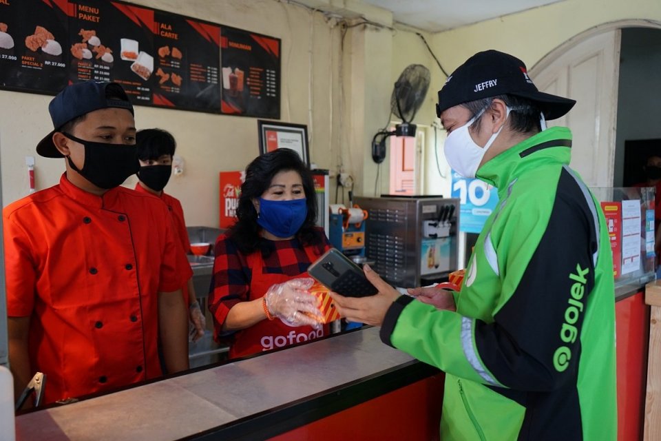 Seorang mitra driver Gojek Jefry Supriyadi menukarkan voucher makan di salah satu mitra UMKM GoFood