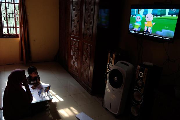 Seorang anak didampingi ibunya belajar dengan melihat tayangan siaran TVRI di rumah mereka, di Deli Serdang, Sumatera Utara, Senin (13/4/2020). 