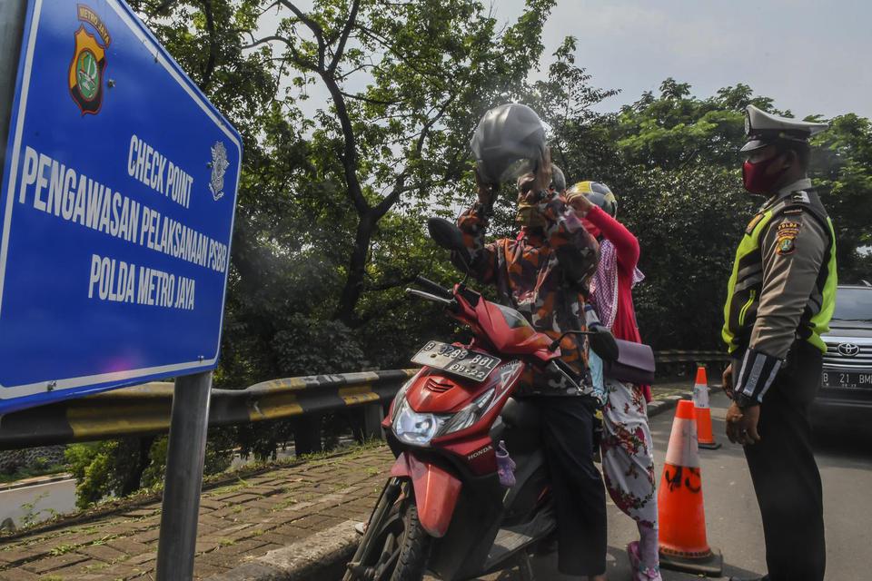 Petugas Polisi menghimbau pengguna kendaraan bermotor saat melakukan Pengawasan Pelaksanaan PSBB terkait penganggulan penyebaran COVID-19 bagi masyarakat yang akan masuk ke Ibu Kota Jakarta di perbatasan Depok-DKI Jakarta, Senin (13/4/2020). Dalam pengawa